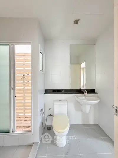 Modern bathroom with sleek fixtures and large mirror in a bright, minimalist design.