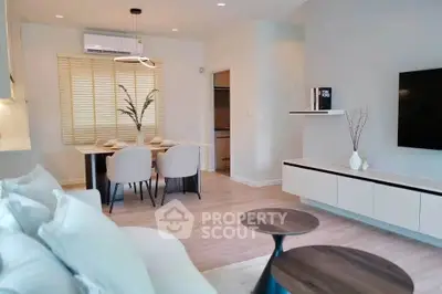 Modern living room with stylish decor and dining area, featuring neutral tones and contemporary furniture.