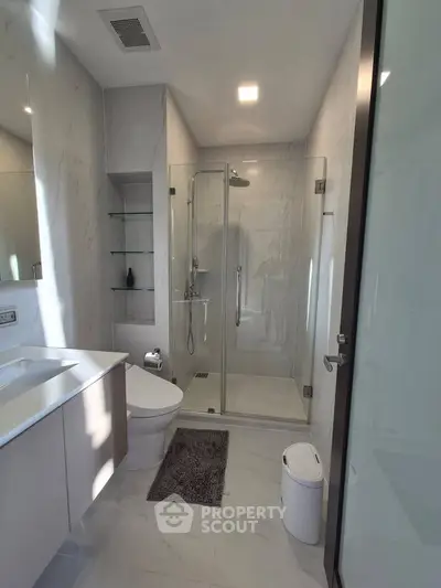 Modern bathroom with glass shower and sleek fixtures in luxury apartment