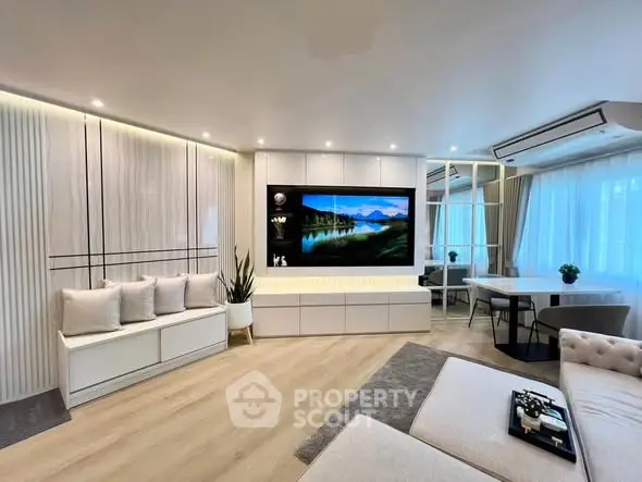 Modern living room with stylish decor and large TV, featuring cozy seating and elegant lighting.