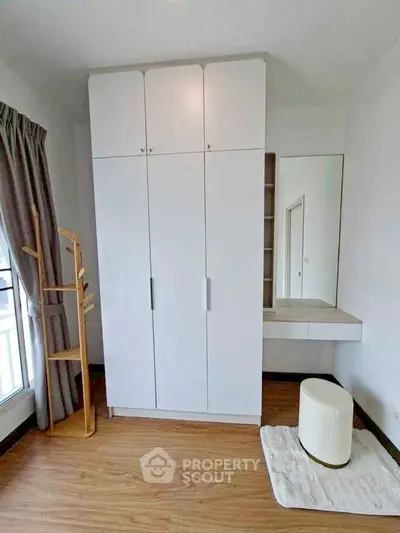 Modern bedroom with sleek white wardrobe and stylish wooden floor