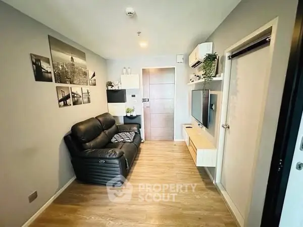 Modern living room with sleek black sofa and stylish wall art in a cozy apartment.