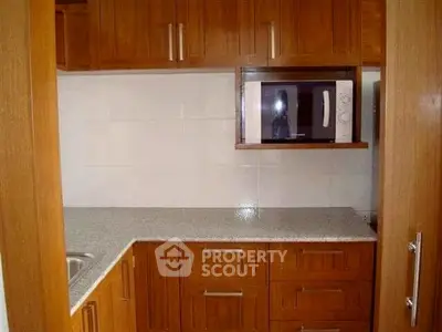 Charming kitchen with wooden cabinets and built-in microwave, perfect for modern living.