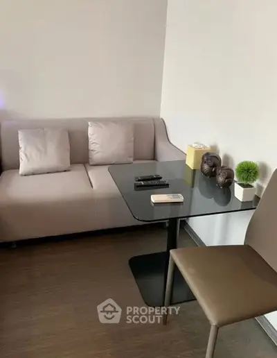 Cozy living room with modern sofa and sleek glass table, perfect for relaxation.