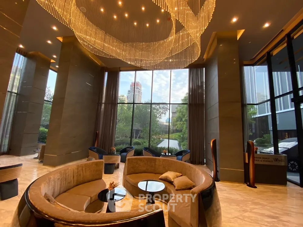 Luxurious high-ceiling lobby with elegant chandelier and plush seating, offering a stunning garden view.