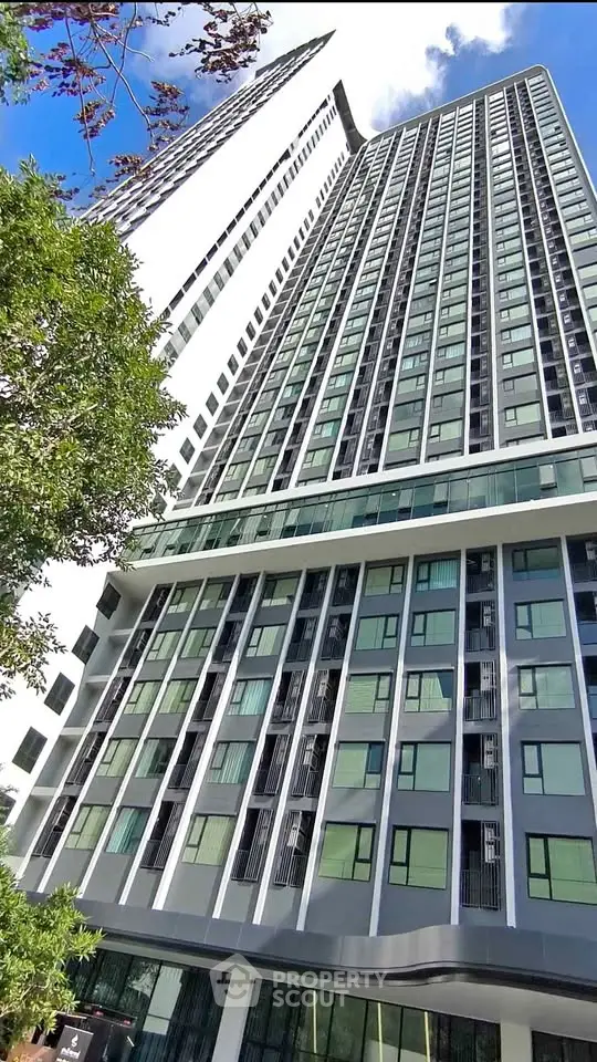 Stunning modern high-rise building with sleek glass facade and lush greenery, perfect for urban living.
