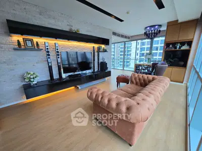 Luxurious living room with modern entertainment center and plush sofa, featuring floor-to-ceiling windows and elegant decor.