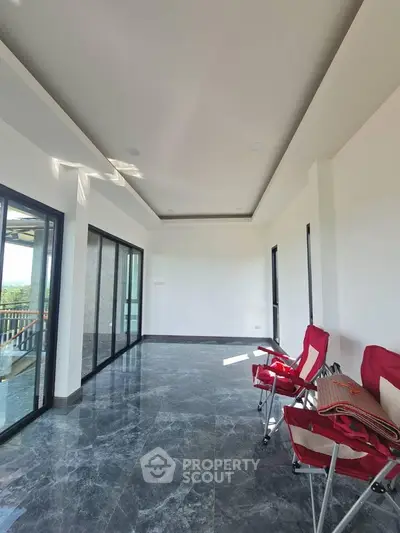 Spacious modern living room with large windows and marble flooring, offering abundant natural light and scenic views.