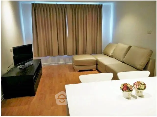 Modern living room with cozy sectional sofa and flat-screen TV, perfect for relaxation.
