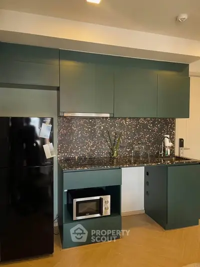 Modern kitchen with sleek dark cabinets, terrazzo backsplash, and built-in appliances in a stylish apartment.