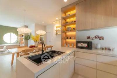 Modern kitchen with open layout and stylish dining area, featuring elegant lighting and sleek cabinetry.