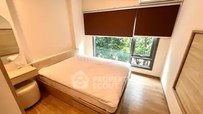 Cozy bedroom with large window and wooden flooring, featuring a comfortable bed and modern decor.