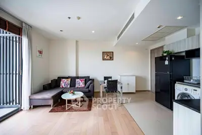 Modern living room with open kitchen, featuring sleek furniture and natural light.