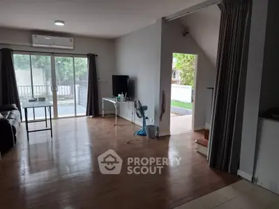 Spacious living room with wooden flooring and large sliding glass doors leading to a balcony.