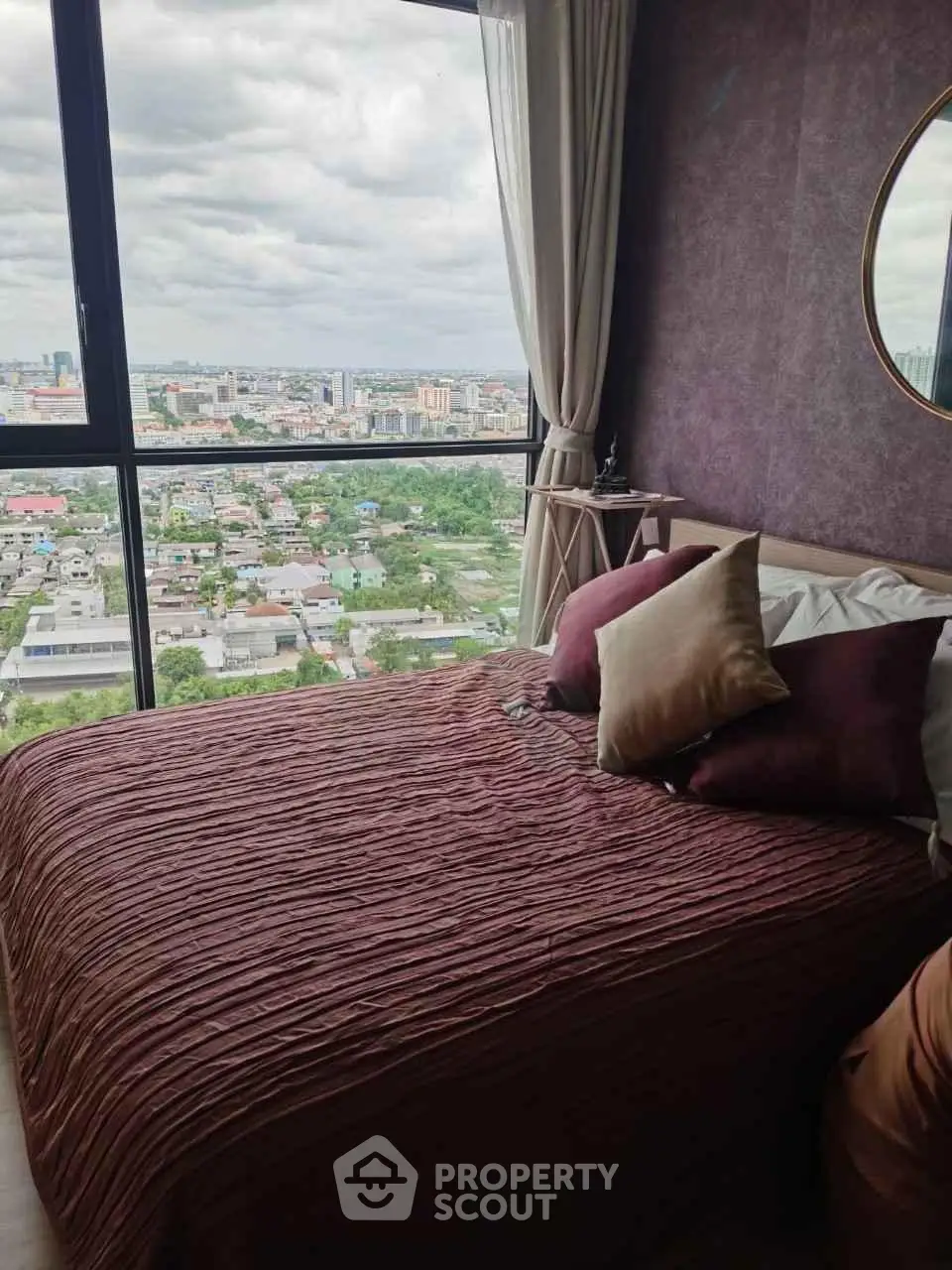 Luxurious bedroom with stunning city view from large window, elegant decor and cozy ambiance.