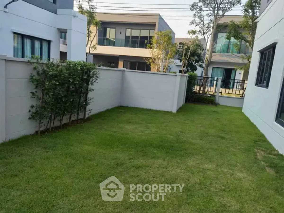 Charming suburban backyard with lush green lawn and modern houses, perfect for family gatherings.