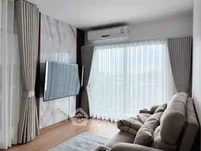 Modern living room with large TV and plush sofa, featuring elegant curtains and natural light.