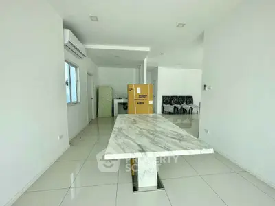 Spacious modern interior with marble table and sleek white tiles, perfect for contemporary living.