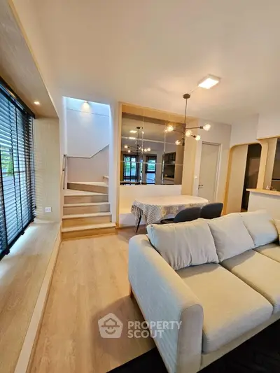 Modern living room with stylish decor and open layout, featuring a cozy sofa and elegant dining area.