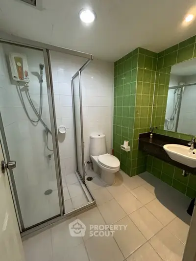 Modern bathroom with glass shower and green tile accent wall