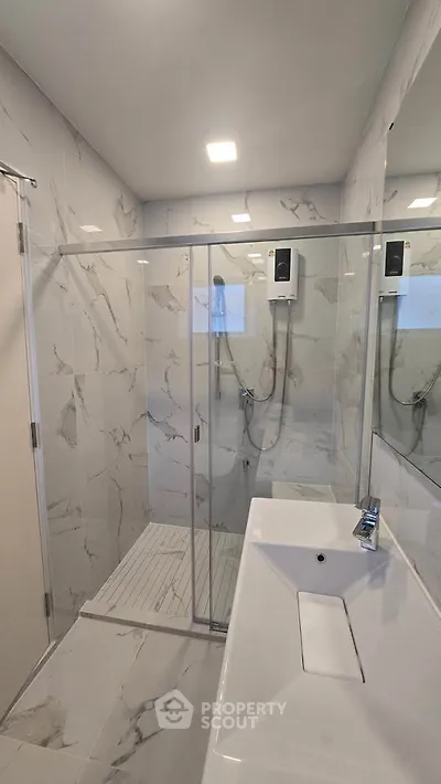 Modern bathroom with glass shower and sleek white fixtures