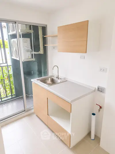 Modern kitchen with sleek cabinetry and balcony view, perfect for urban living.