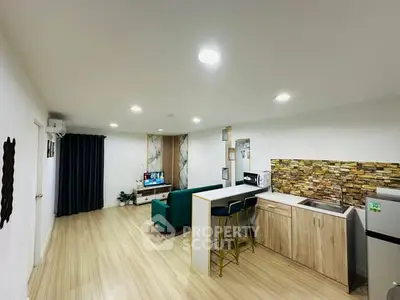 Modern open-layout living room and kitchen with stylish decor and ample lighting.