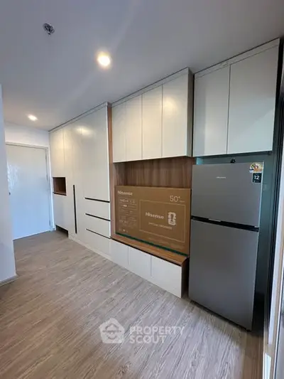Modern kitchen with sleek cabinetry and stainless steel fridge in a bright apartment.