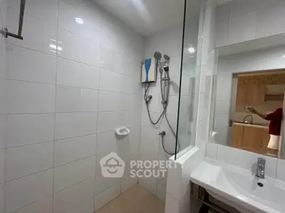 Modern bathroom with sleek white tiles and shower area in a contemporary home.