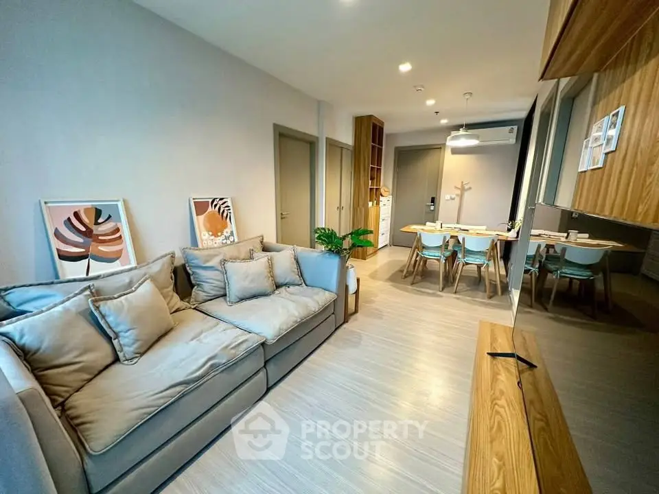 Modern living room with stylish decor and open dining area, featuring cozy seating and elegant lighting.