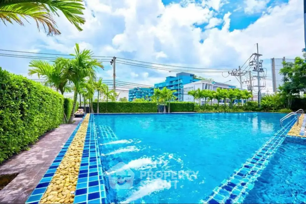 Stunning outdoor pool with lush greenery and clear blue skies, perfect for relaxation.