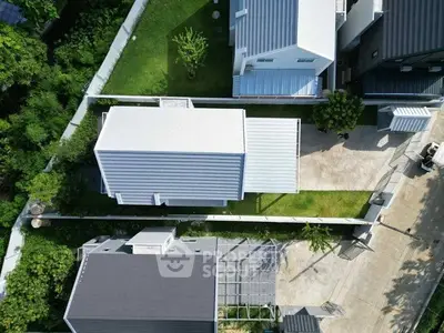 Aerial view of modern residential homes with sleek roofs and green surroundings.