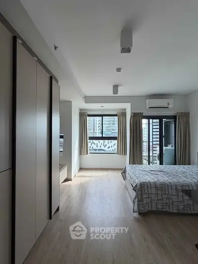 Spacious modern bedroom with large windows and city view, featuring sleek design and ample natural light.