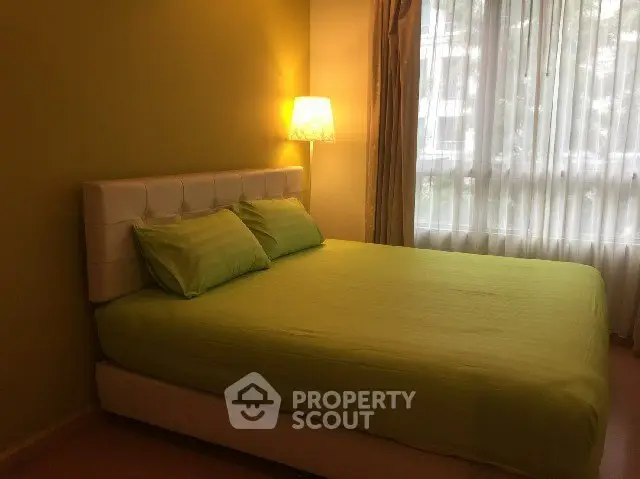Cozy bedroom with green accents and natural light from large window.