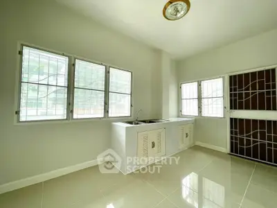 Bright kitchen with large windows and modern sink in a spacious home.