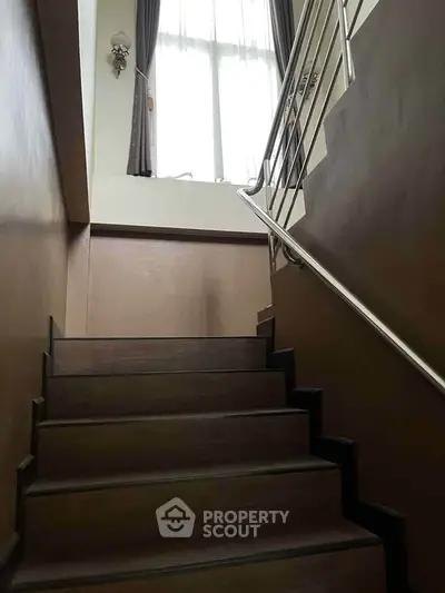 Elegant staircase with modern railing and large window for natural light.