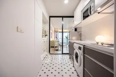 Modern kitchen with sleek appliances and washing machine, open layout to dining area.