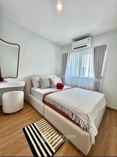 Cozy bedroom with modern decor, featuring a comfortable bed, stylish mirror, and natural light from large window.