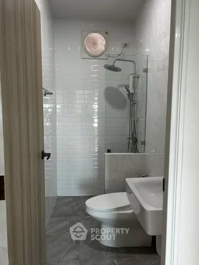 Modern bathroom with sleek fixtures and white tile walls, featuring a shower and toilet.