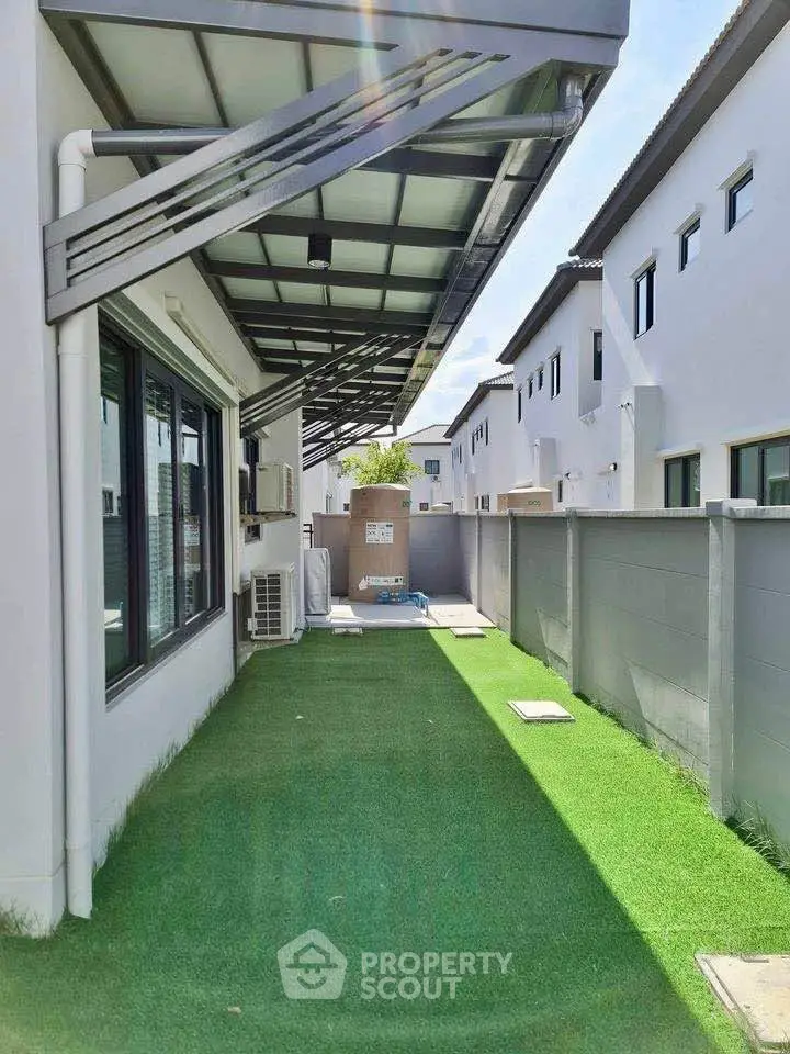Modern townhouse exterior with artificial grass and sleek awning