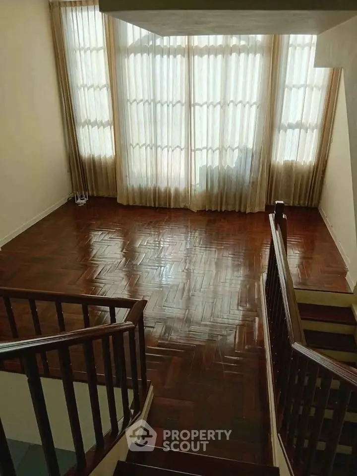 Spacious living room with polished wooden floors and large windows for natural light.