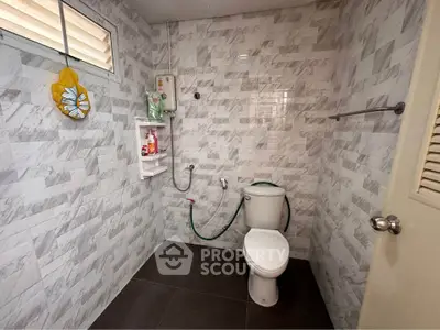 Modern bathroom with tiled walls and essential fixtures in a cozy home setting.