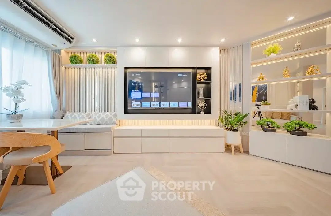 Modern living room with built-in TV, elegant shelving, and stylish decor in a bright, airy space.