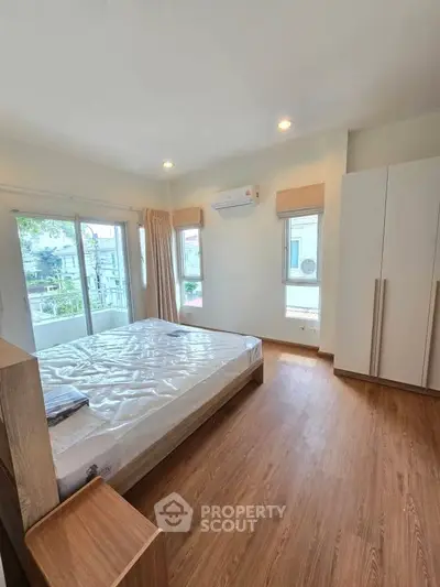 Spacious bedroom with large windows and modern wooden flooring