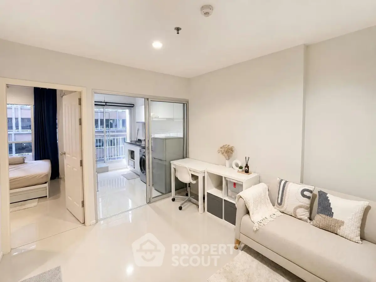 Modern apartment interior with living room, study area, and view into bedroom and kitchen.