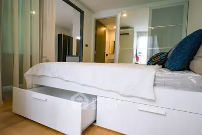 Modern bedroom with sleek storage bed and mirrored closet doors in a stylish apartment.