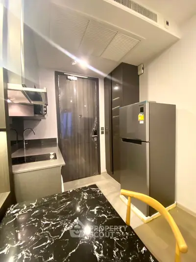 Modern kitchen with sleek design, featuring marble countertop and stainless steel appliances.