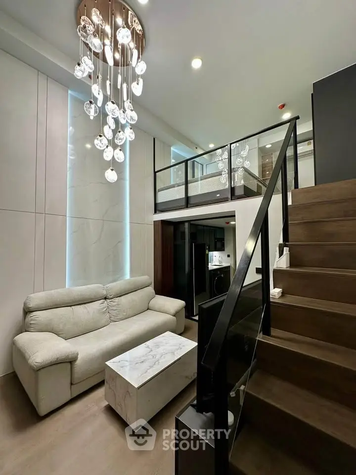Modern loft-style living room with elegant chandelier and cozy sofa, featuring a stylish staircase and open layout.