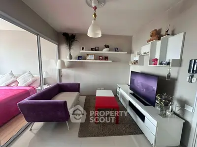 Modern living room with vibrant purple sofa and red coffee table, open to cozy bedroom.