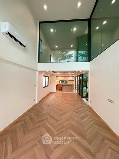 Spacious modern living room with high ceilings and elegant wood flooring, featuring a sleek open kitchen design.